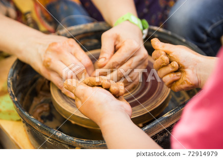 A close up view on ceramic production process on potter's wheel with children. Clay crafts with kids concept 72914979