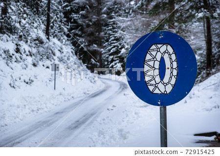 Frozen slippery road covered with snow through alpine forest. Frozen slippery road covered with snow through alpine forest. 72915425