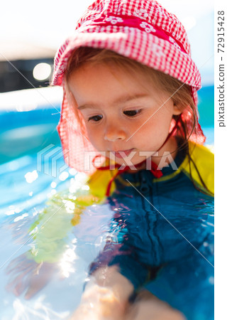 Child in Inflatable swimming pool in backyard. Child in Inflatable swimming pool in backyard. 72915428