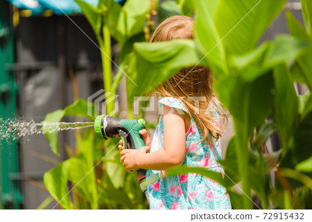 2-3 year old girl with garden hose water the plants plants. 2-3 year old girl with garden hose water the plants plants. 72915432
