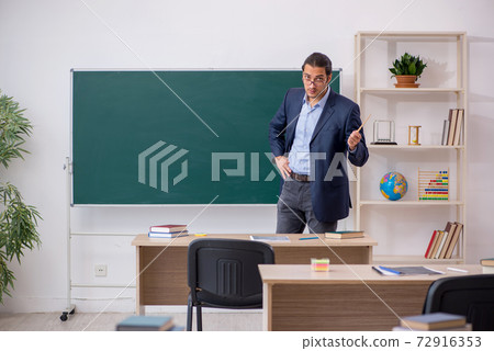 Young male teacher in front of green board 72916353