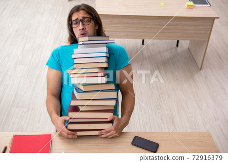 Young male student and a lot of books in the class 72916379
