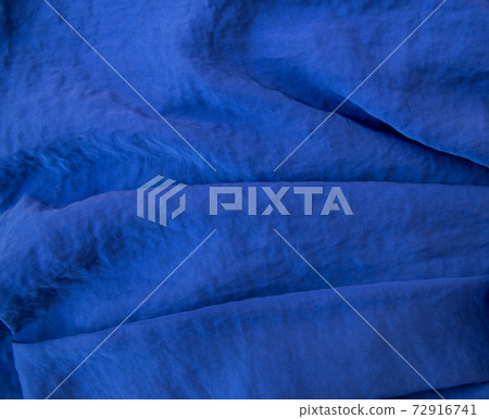Luxurious expensive blue fabric as an elegant background with beautiful tints of light. Soft folds fall and create light waves Luxurious expensive blue fabric as an elegant background with beautiful tints of light. Soft folds fall and create light waves 72916741