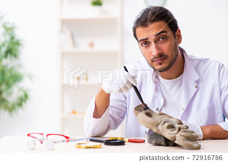 Young male archaeologist studying ancient african stonemask 72916786