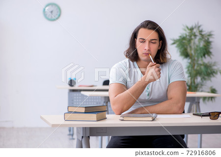 Young male student smoking cigarettes in the classroom 72916806