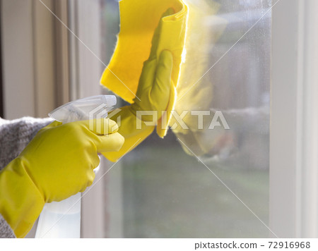 Cleaning a window with spray detergent, Yellow rubber gloves and dish cloth on work surface concept for hygiene, business and health concept Cleaning a window with spray detergent, Yellow rubber gloves and dish cloth on work surface concept for hygiene, business and health concept 72916968