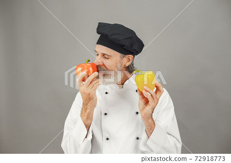 Chef in white uniform over gray background Chef in white uniform over gray background 72918773