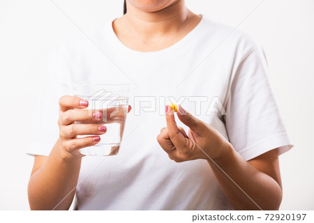 Woman hold fish oil vitamin drugs in hand ready take medicines with a glass of water 72920197
