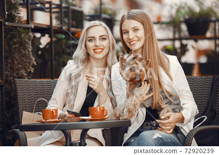 Elegant women sitting in a summer cafe 72920239