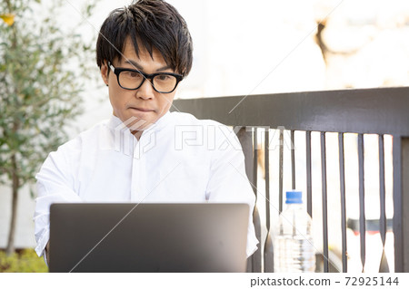 [Worcation] A man who concentrates on work on the hotel terrace 72925144