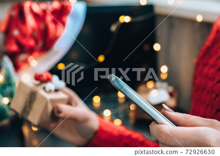 Christmas online shopping. Female buyer makes order on mobile phone. Woman buy presents, prepare to xmas. Winter holidays sales. Christmas online shopping. Female buyer makes order on mobile phone. Woman buy presents, prepare to xmas. Winter holidays sales. 72926630