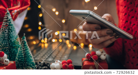 Christmas online shopping. Female buyer makes order on mobile phone. Woman buy presents, prepare to xmas. Winter holidays sales. Christmas online shopping. Female buyer makes order on mobile phone. Woman buy presents, prepare to xmas. Winter holidays sales. 72926632