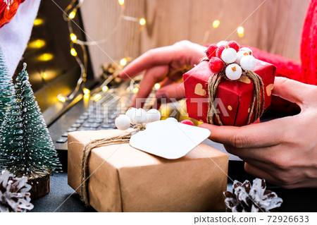 Woman holding small present box in hand and using search by laptop. Christmas Concept. Online shopping. Holiday sale. Woman holding small present box in hand and using search by laptop. Christmas Concept. Online shopping. Holiday sale. 72926633
