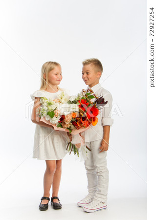 Studio portrait boy gives girl festive bouquet, congratulatory concept, white background, copy space 72927254