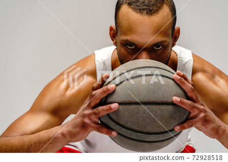 Muscular african american sportsman playing basketball over light grey background Muscular african american sportsman playing basketball over light grey background 72928518