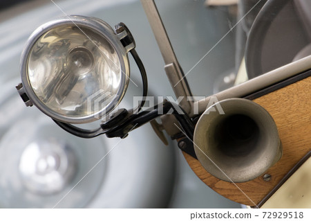 The headlight with horn on the old car. Veteran car with the classical klaxon and reflector. 72929518
