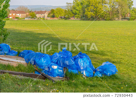 Fly-tipped disused rubbish in blue plastic bags, illegally dumped in football field. Stockport UK. Fly-tipped disused rubbish in blue plastic bags, illegally dumped in football field. Stockport UK. 72930443