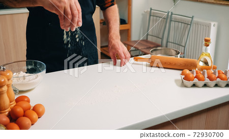 Grandfather sieving flour on wooden table Grandfather sieving flour on wooden table 72930700