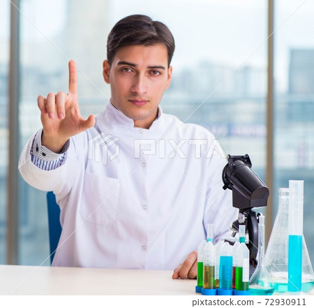 Young chemist pressing virtual buttons in lab Young chemist pressing virtual buttons in lab 72930911