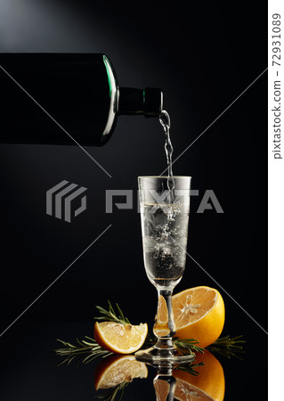Gin with lemon and rosemary on a black reflective background. Gin with lemon and rosemary on a black reflective background. 72931089