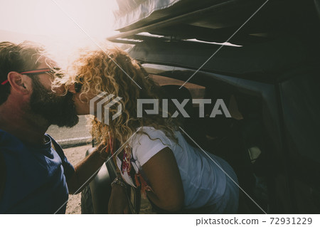 Adult couple in love kiss outside the car and travel together - concept of free and happy lifestyle for beautiful people traveling and enjoying life Adult couple in love kiss outside the car and travel together - concept of free and happy lifestyle for beautiful people traveling and enjoying life 72931229