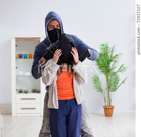 Armed man assaulting young woman at home 72931327