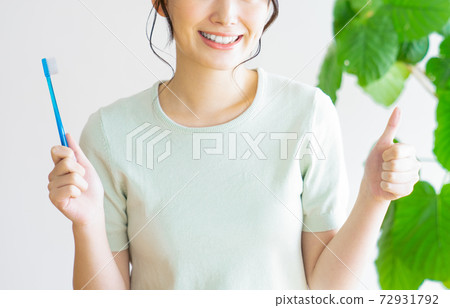 Young woman holding a toothbrush and thumbs up 72931792