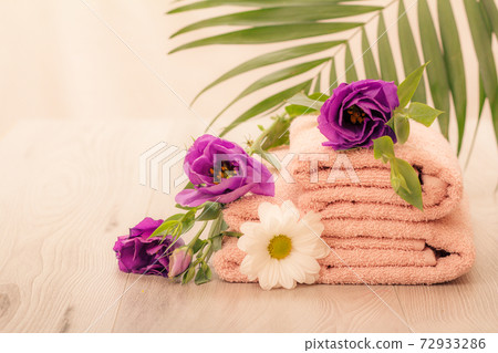 Stack of soft terry towels with flowers on wooden boards Stack of soft terry towels with flowers on wooden boards 72933286