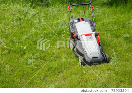 Lawn mower on green grass in the garden 72933294