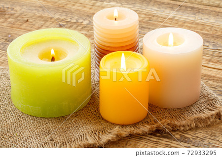 Burning candles on sackcloth and wooden background. Burning candles on sackcloth and wooden background. 72933295