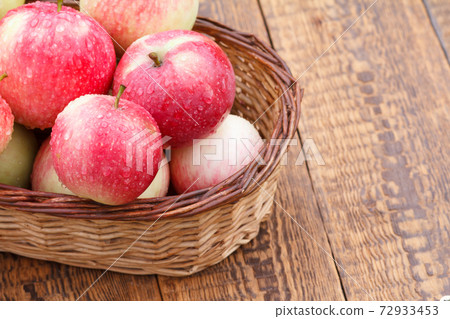 Red apples in the wicker basket on wooden boards 72933453
