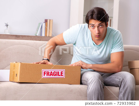 Man opening fragile parcel ordered from internet Man opening fragile parcel ordered from internet 72933902