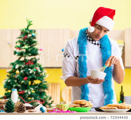 Young chef husband working in kitchen at Christmas eve Young chef husband working in kitchen at Christmas eve 72934430