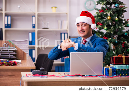 Young male employee celebrating Christmas at workplace 72934579