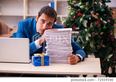 Young male employee working in the office at Chrismas Young male employee working in the office at Chrismas 72934590