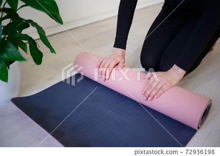 young woman unfolds yoga mat before practice 72936198