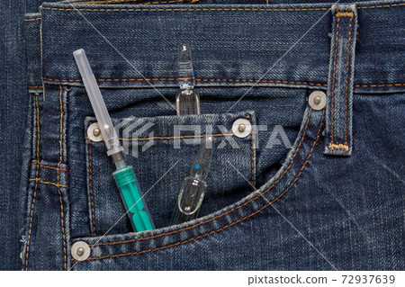 Syringe and ampullas lying in side pocket of jeans Syringe and ampullas lying in side pocket of jeans 72937639