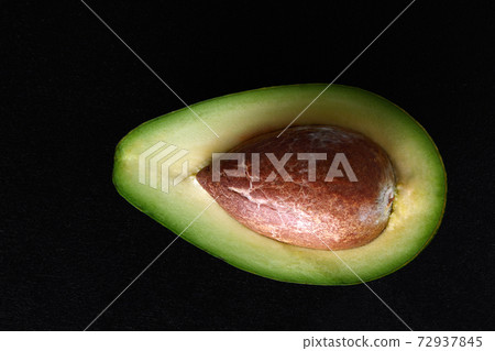 Macro shot of fresh avocados cut in a half on the black background Macro shot of fresh avocados cut in a half on the black background 72937845