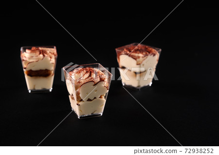 Three tiramisu in glasses in row isolated on black. Three tiramisu in glasses in row isolated on black. 72938252