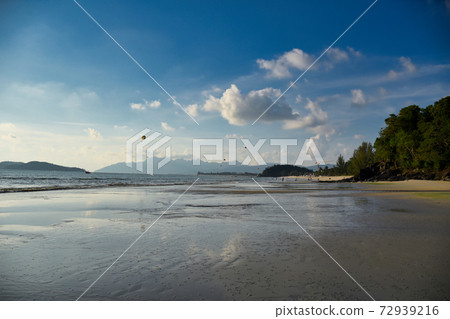 Waves of the azure Andaman sea under the blue sky reaching the shores of the sandy beautiful exotic and stunning Cenang beach in Langkawi island 72939216