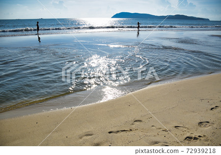 Waves of the azure Andaman sea under the blue sky reaching the shores of the sandy beautiful exotic and stunning Cenang beach in Langkawi island 72939218