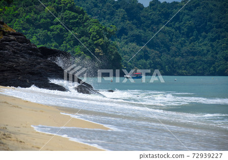 Waves of the azure Andaman sea under the blue sky reaching the shores of the sandy beautiful exotic and stunning Cenang beach in Langkawi island 72939227