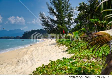 Waves of the azure Andaman sea under the blue sky reaching the shores of the sandy beautiful exotic and stunning Cenang beach in Langkawi island Waves of the azure Andaman sea under the blue sky reaching the shores of the sandy beautiful exotic and stunning Cenang beach in Langkawi island 72939234