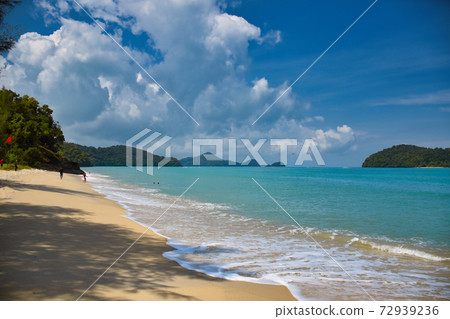 Waves of the azure Andaman sea under the blue sky reaching the shores of the sandy beautiful exotic and stunning Cenang beach in Langkawi island Waves of the azure Andaman sea under the blue sky reaching the shores of the sandy beautiful exotic and stunning Cenang beach in Langkawi island 72939236