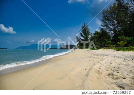 Waves of the azure Andaman sea under the blue sky reaching the shores of the sandy beautiful exotic and stunning Cenang beach in Langkawi island Waves of the azure Andaman sea under the blue sky reaching the shores of the sandy beautiful exotic and stunning Cenang beach in Langkawi island 72939237