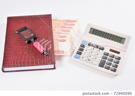Magnifying glass lies on the business calendar with bookmarks out of the money near the calculator 72940090