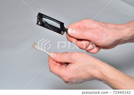 Hands of an electrician look at the compressed twisted pair thro 72940142