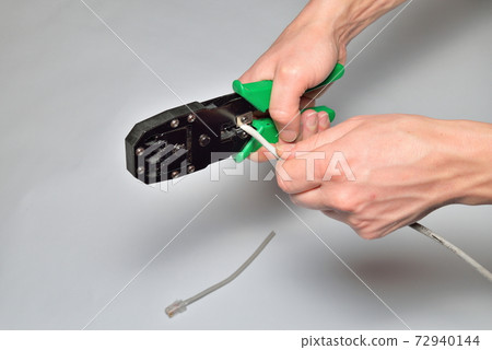 Hands of an electrician cut off the computer twisted pair tongs Hands of an electrician cut off the computer twisted pair tongs 72940144