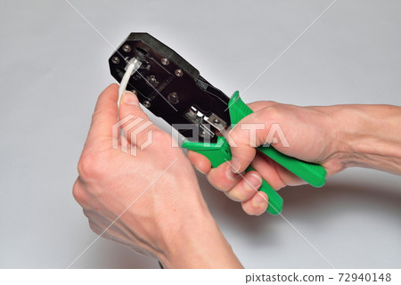 Hands of the installer, computer network, fix the connector on the cable. Hands of the installer, computer network, fix the connector on the cable. 72940148