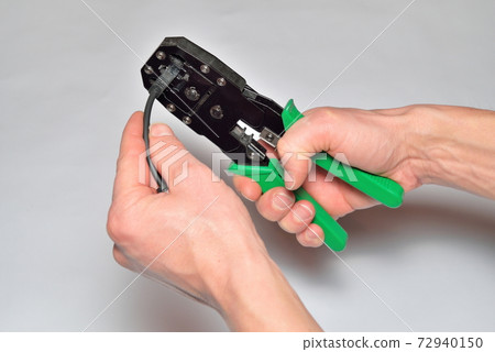 Hands of the installer of computer networks crimped connector on the cable 72940150